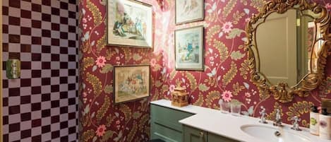 A bathroom with floral wallpaper, a checkered floor, a sink, and a toilet.