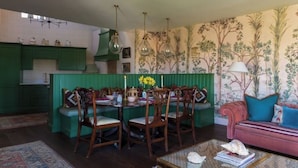 Un coin repas agrémenté d’un mur vert, de chaises en bois et d’une table dressée pour quatre personnes.