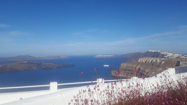 A coastal landscape with a white building, a body of water, and distant islands.