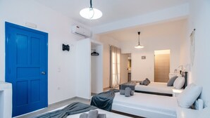 A hotel room with a blue door, two beds, a shower area, and a bathroom with a mirror.