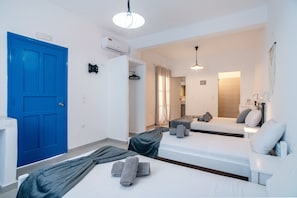A hotel room with a blue door, two beds, a shower area, and a bathroom with a mirror.