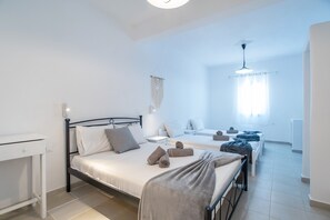 A bedroom with a single bed, a bedside table, a desk, and a window with curtains.
