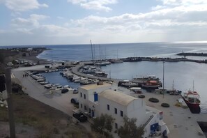 A marina with boats docked, a road leading to a building, and a clear view of the sea. - Two-Bedroom Apartment with Mountain View, Wi-Fi & Air Conditioning (Perissa)
