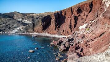 A coastal landscape with rocky cliffs, clear blue water, and a small boat.
