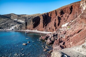 A coastal landscape with rocky cliffs, clear blue water, and a small boat.