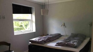 A bedroom with a bed, a chair, a window, and a hanging light fixture. - 5 Star Holiday Home in Frederikshavn (Frederikshavn)