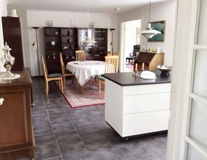 Ein Essbereich mit einem runden Tisch, Stühlen, einem Teppich und einer Kücheninsel mit Arbeitsplatte.