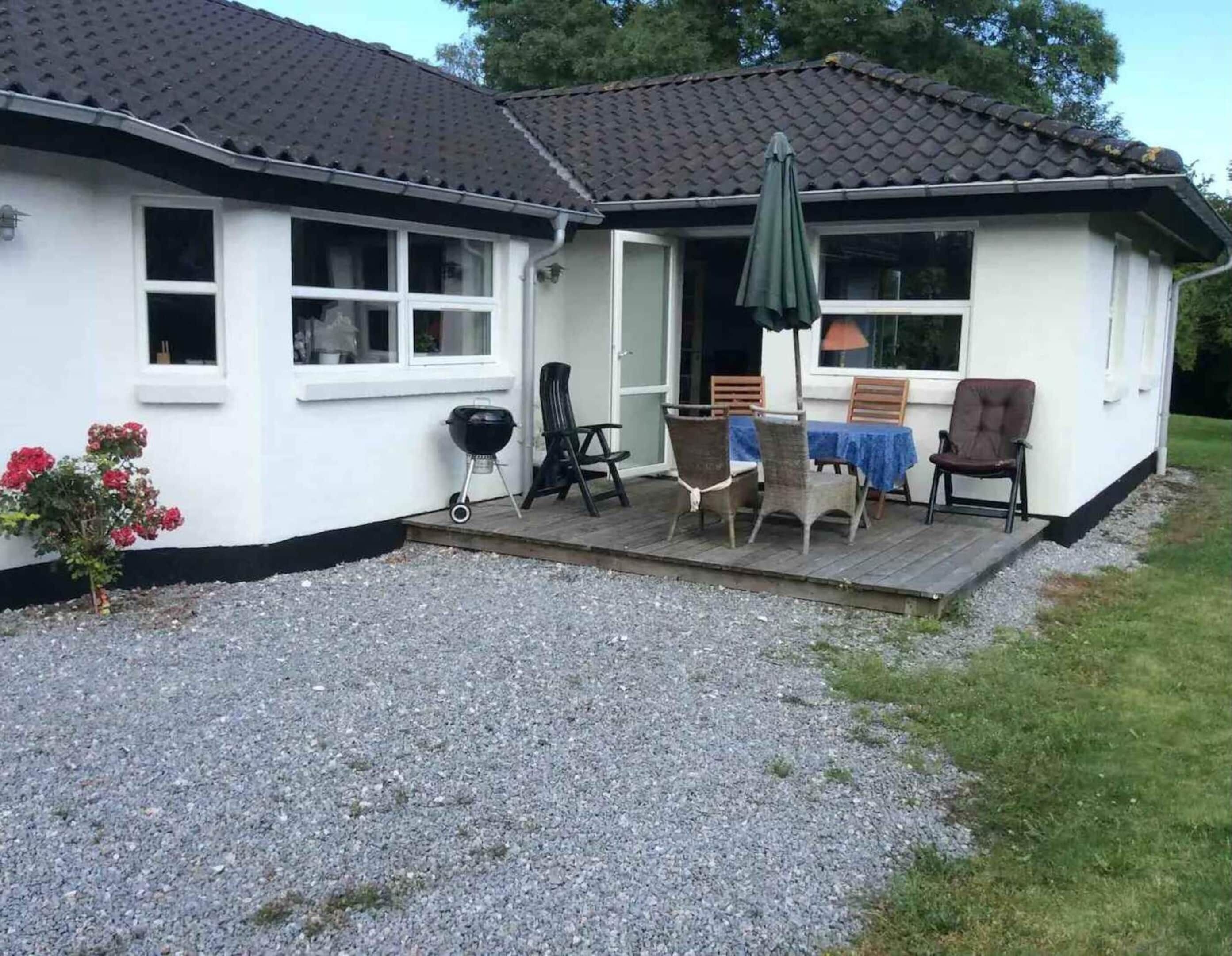 Een gelijkvloers huis met een veranda, een barbecue en zitplaatsen buiten.