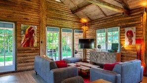 A log cabin interior with a dining area, sofas, a TV, and artwork on the walls. - Spacious Wooden Chalet With Covered Terrace (Baarle-Nassau)