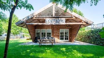 A wooden cabin with a sloped roof, a picnic table, and a sign reading 'DE PAUL ENTRANTS'.