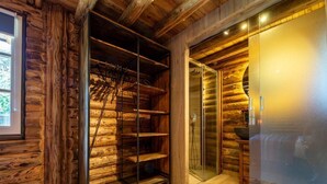 A log cabin interior with a glass door leading to a bathroom, wooden flooring, and a metal shelving unit. - Spacious Wooden Chalet With Covered Terrace (Baarle-Nassau)