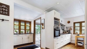 A modern kitchen with white cabinets, a wooden floor, and a view of the outdoors through large windows. - 5 Star Holiday Home in Nykobing Sj (Sjællands Odde)