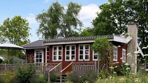 A red wooden house with white trim, a brick chimney, and a wooden fence. - 5 Star Holiday Home in Nykobing Sj (Sjællands Odde)