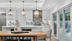 A modern kitchen with a central island, pendant lights, and a dining area with a bench.