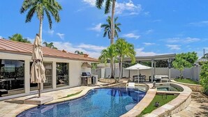 A swimming pool with a curved design, surrounded by stone tiles and palm trees.