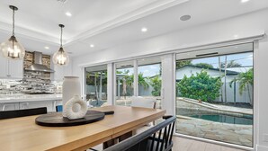 A modern kitchen with a large island, a dining area with a bench, and a view of a swimming pool.