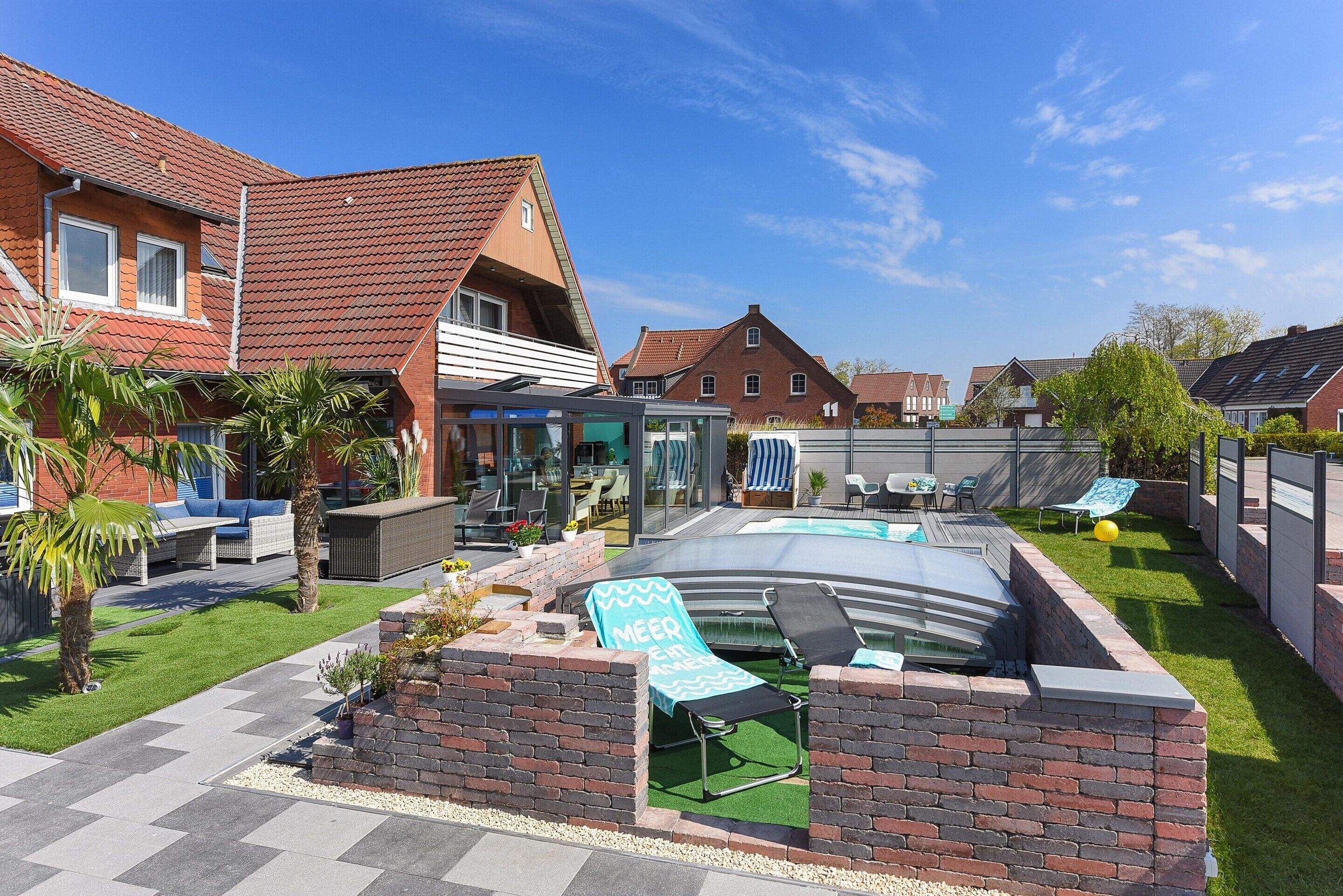 A residential backyard with a swimming pool, lounge chairs, and a brick wall.