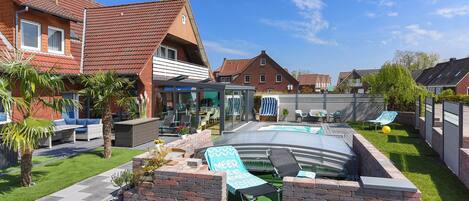 A residential backyard with a swimming pool, lounge chairs, and a brick wall.