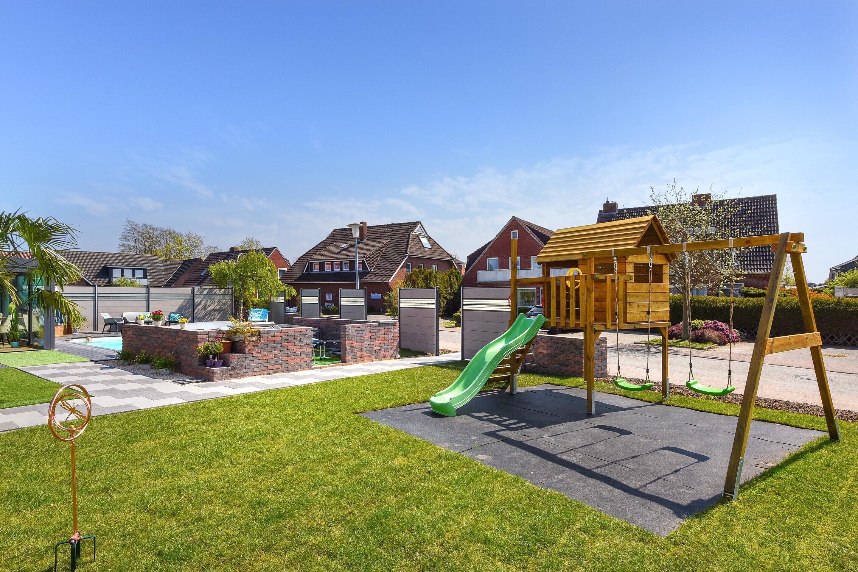 A residential area with a playground featuring a slide and swings, a brick patio, and a lawn.