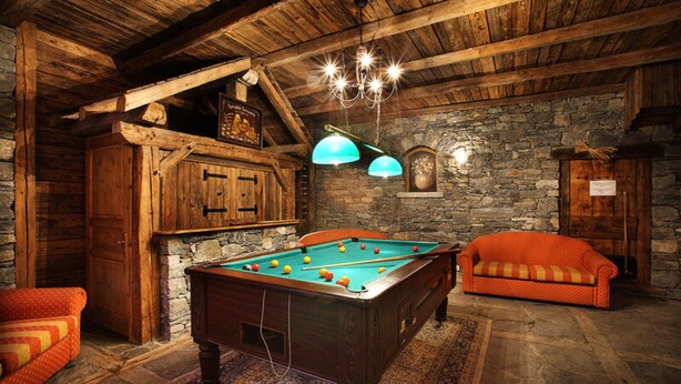 Une pièce chaleureuse avec une table de billard, des meubles en bois et des murs en pierre.
