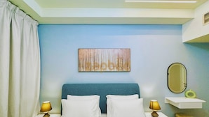 A bedroom with a bed, two bedside tables, a nightstand, a wall-mounted mirror, and a decorative wall piece. - RAK F 202 (Ras Al Khaimah)