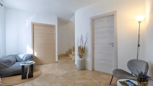 Un salon moderne comprenant un canapé, une petite table d’appoint, un fauteuil, une lampe et un escalier menant à une autre pièce.