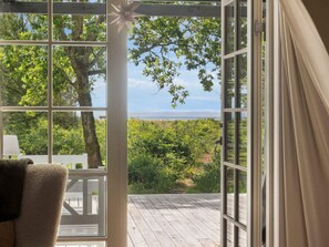 A room with a large window overlooking a deck and a scenic view of trees and a body of water. - 4 Star Holiday Home in Hurup Thy (Hurup Thy)