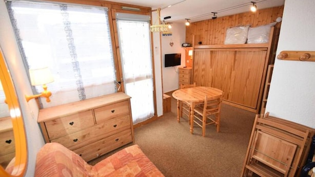 A cozy room with a wooden dresser, a round table, and a bench. - Studio for 3 People - LES Hameaux 2 - Plagne Villages (La Plagne-Tarentaise)