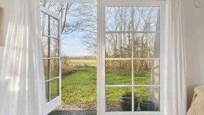 A room with a large window offering a view of a grassy field and trees. - 5 Star Holiday Home in Nykobing M (Nykobing Mors)