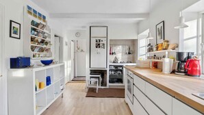 A modern kitchen with white cabinetry, a wooden countertop, and various kitchen appliances. - 5 Star Holiday Home in Nykobing M (Nykobing Mors)