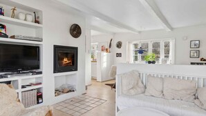 A modern living room with a fireplace, white furniture, and a television. - 5 Star Holiday Home in Nykobing M (Nykobing Mors)