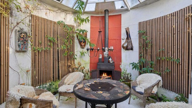 A cozy outdoor patio with a glass ceiling, a fireplace, wicker furniture, and decorative wall art. - 5 Star Holiday Home in Nykobing M (Nykobing Mors)