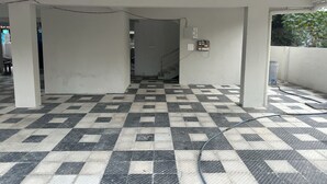A corridor with a checkered floor, white walls, and a staircase leading to another area. - CC Elite Homestay (Hyderabad)