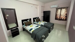 A bedroom with two beds, a wardrobe, a mirror, and a ceiling fan. - CC Elite Homestay (Hyderabad)