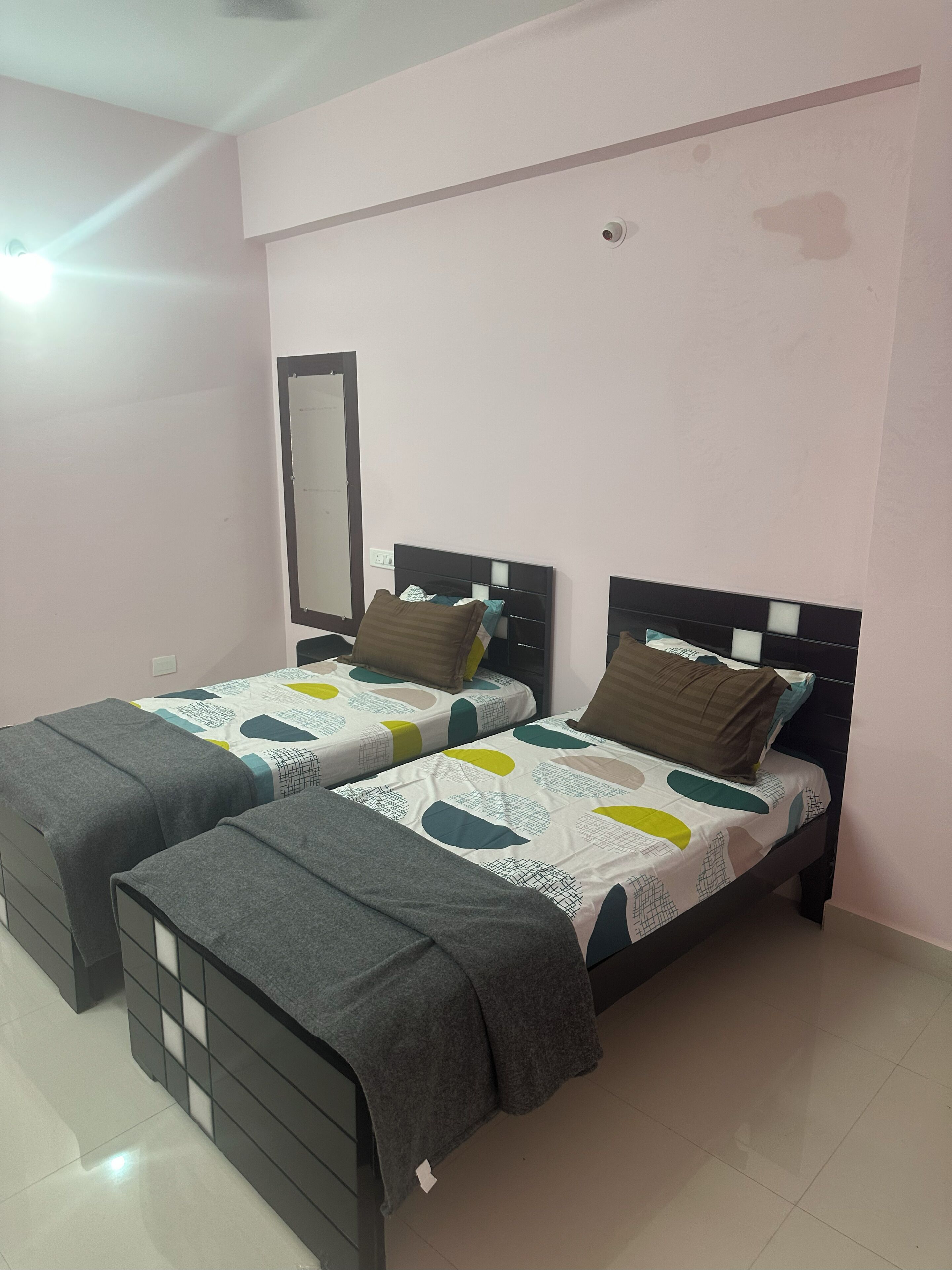 Dormitorio doble con dos camas, cada una con cabecero, espejo y ventana.