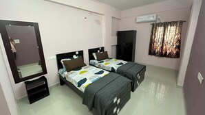 A bedroom with two beds, a wardrobe, a mirror, and an air conditioning unit. - CC Elite Homestay (Hyderabad)