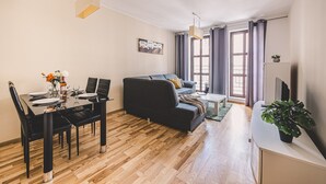 Un soggiorno moderno con un tavolo da pranzo, un divano nero e una TV su un mobile.