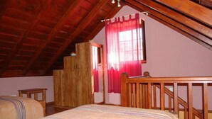 A bedroom with a wooden ceiling, a bed with a striped bedspread, a wooden wardrobe, and a window with red curtains. - Charming Casa Cabrera with stunning sea views and spacious terrace (Fuencaliente de La Palma)