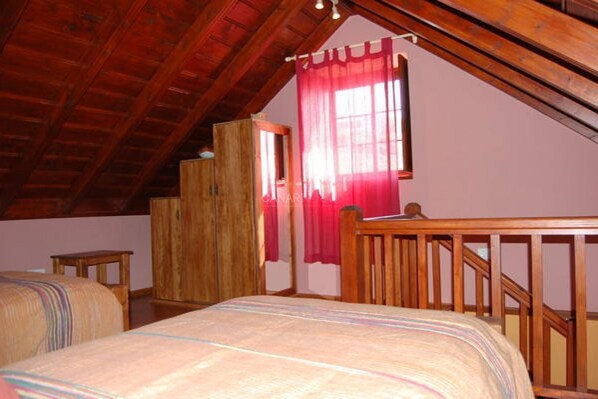 A bedroom with a wooden ceiling, a bed with a striped bedspread, a wooden wardrobe, and a window with red curtains. - Charming Casa Cabrera with stunning sea views and spacious terrace (Fuencaliente de La Palma)