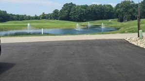 Un campo da golf con uno stagno, un vialetto sterrato e un lampione.