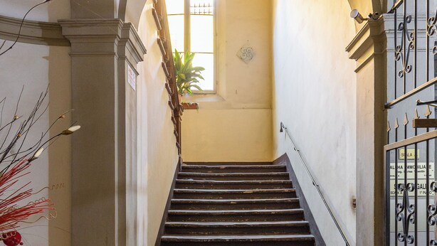 A staircase with a wrought iron railing, leading to a room with a window and a door. - Montegrappa Apartment by Wonderful Italy (Bologna)