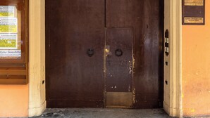 A large, dark wooden door with a white arch above it, set in a building with orange walls. - Montegrappa Apartment by Wonderful Italy (Bologna)