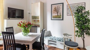 A modern living room with a dining table, chairs, a TV, a bookshelf, and a potted plant. - Montegrappa Apartment by Wonderful Italy (Bologna)