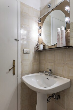 Een badkamer met een wit wastafel, een spiegel met verlichting en een handdoekhouder.