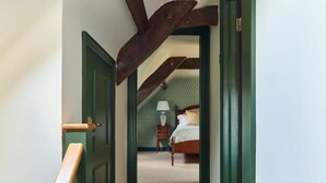 Un pasillo que conduce a un dormitorio con una cama, una mesita de noche y una lámpara.
