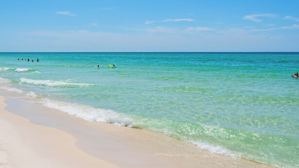 Ein Strand mit klarem türkisblauem Wasser und einem Sandufer.