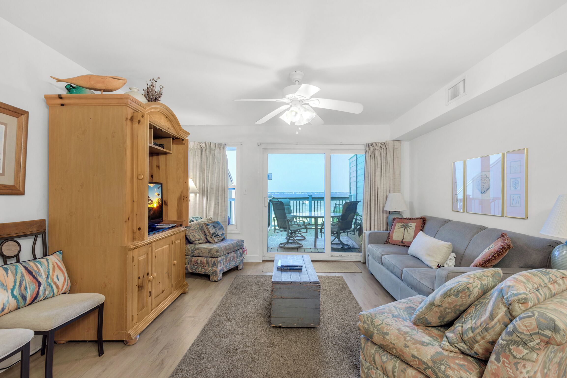 Een ruime woonkamer met een houten kast, een bank, een bijzettafeltje en uitzicht op het balkon.