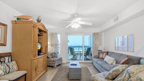 Ein geräumiges Wohnzimmer mit Holzschrank, einer Couch, einem Couchtisch und Blick auf den Balkon.