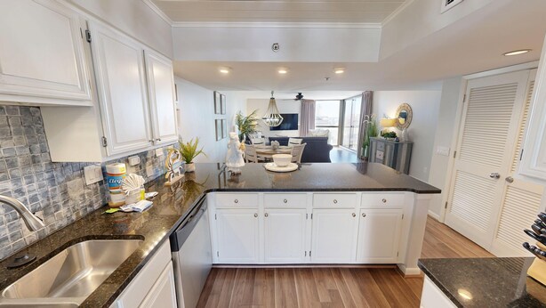 A modern kitchen with white cabinetry, a granite countertop, and a central island. - Mainsail 341 2 Bedroom Condo (Miramar Beach)