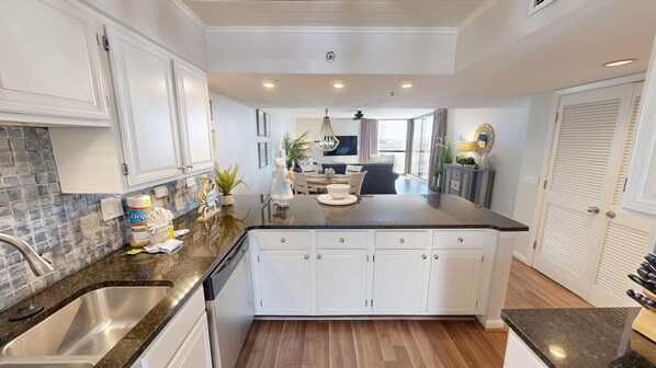 Una cocina moderna con armarios blancos, encimera de granito y una isla central.